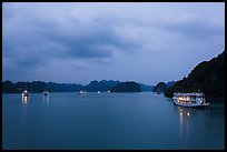 View of bay with lights of anchored tour boats at dawn. Halong Bay, Vietnam (color)