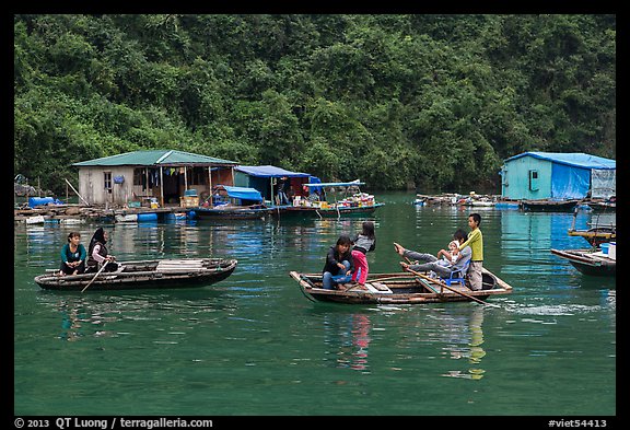 Villagers move between floating houses by rowboat. Halong Bay, Vietnam