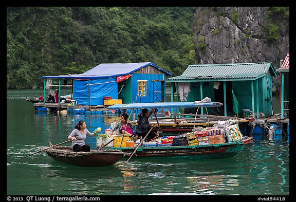 Woman buying produce from grocery boat, Vung Vieng village. Halong Bay, Vietnam