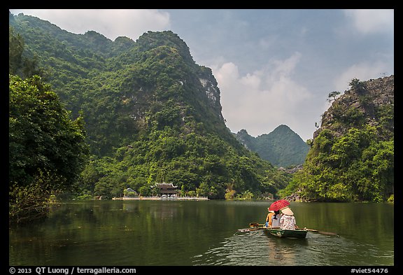 Boat journeying below tall lush cliffs, Trang An. Ninh Binh,  Vietnam