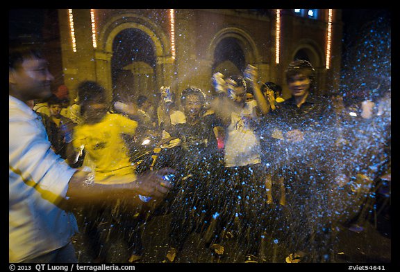 Revellers celebrating with spray in front of Notre Dame Cathedral on Christmas Eve. Ho Chi Minh City, Vietnam