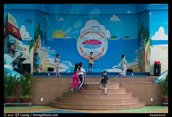 Children on stage next to militaristic mural, Dam Sen Water Park, district 11. Ho Chi Minh City, Vietnam
