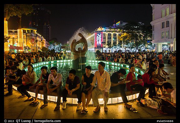People sitting on fountain at night, New Year eve. Ho Chi Minh City, Vietnam