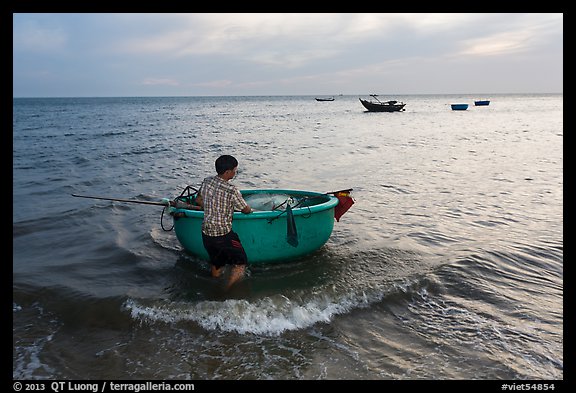 Man holding coracle boat. Mui Ne, Vietnam (color)