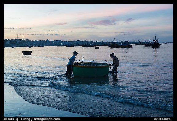 Fishermen pushing coracle boat at dawn. Mui Ne, Vietnam