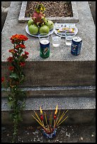Grave with offerings of incense, flowers, drinks, fruit, and fake money. Ben Tre, Vietnam (color)