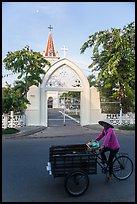 Woman bicycling in front of church. Tra Vinh, Vietnam (color)