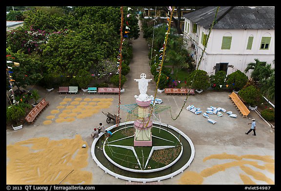 View of drying rice and statue from church tower. Tra Vinh, Vietnam