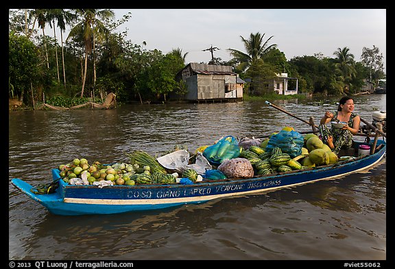Woman with boat loaded with produce eating noodles. Can Tho, Vietnam