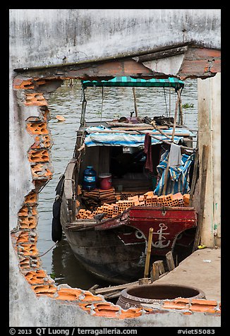Boat loaded with bricks seen from brick wall opening. Can Tho, Vietnam