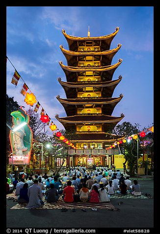 Worshippers and seven story  Quoc Tu pagoda at dusk. Ho Chi Minh City, Vietnam (color)