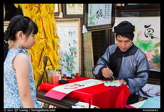 Caligrapher draws Tet greetings as woman looks on. Ho Chi Minh City, Vietnam (color)