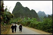 Villagers in traditional garb walking down the road with limestone peaks in the background, Ma Phuoc Pass area. Northeast Vietnam ( color)