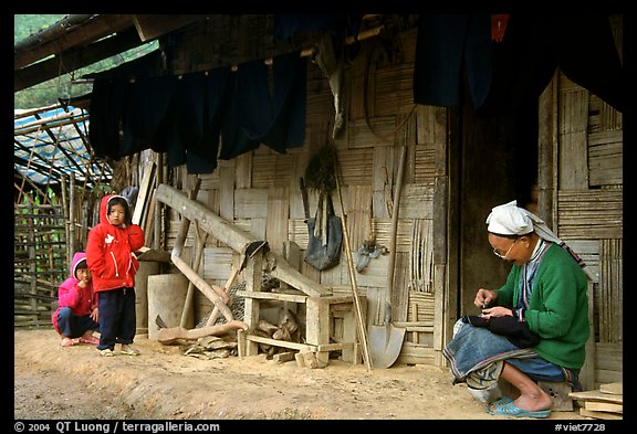 Elderly woman sewing  on her doorstep as kids look up. Northeast Vietnam