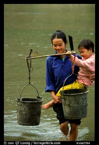 Woman of the Tay minority carrying crossing the river with child, Ba Be Lake. Vietnam (color)