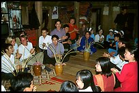 Guests in a thai house gather around jars of rau can alcohol, Ban Lac, Mai Chau. Northwest Vietnam