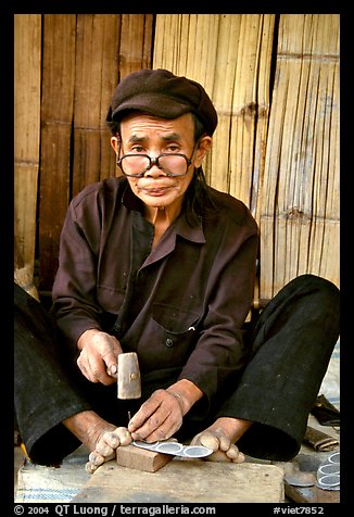 Black Dzao man making the decorative coins used in the children hats, between Tam Duong and Sapa. Northwest Vietnam (color)