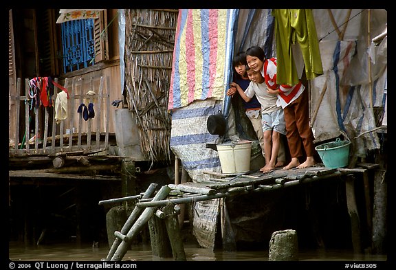 Children peering from their waterfront house. Can Tho, Vietnam